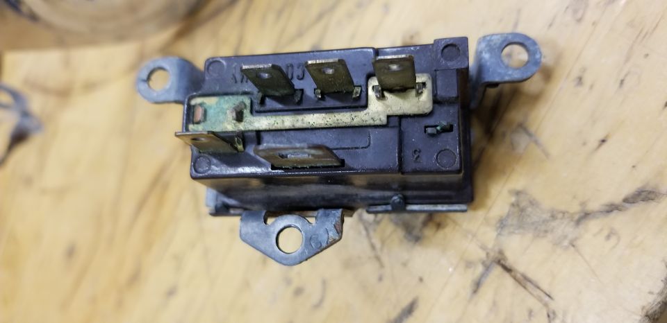 Black electrical relay with metal mounting tabs and brass terminals