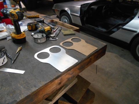 1992 Ford Bronco - A silver DeLorean DMC-12 sits with its door open, next to a workbench with tools and a custom part template.