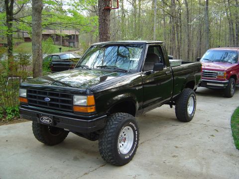 1989 Ford Ranger - A lifted 1989 Ford Ranger pickup truck is parked in a driveway next to another vehicle.