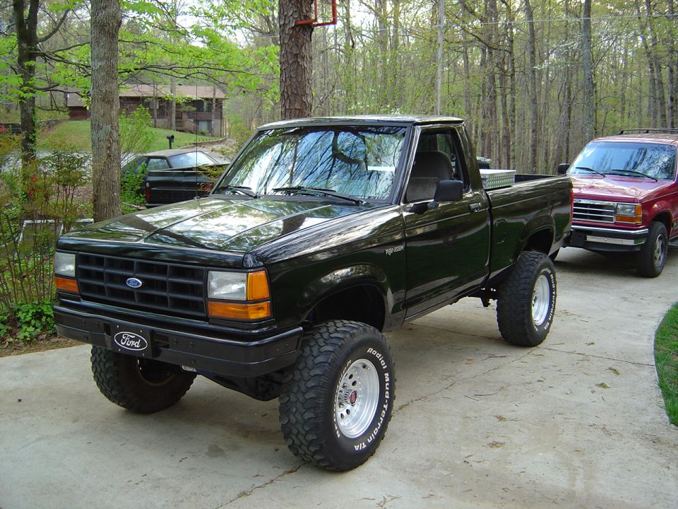 Lifted black Ford Ranger regular cab on BFGoodrich mud-terrain tires in a wooded driveway