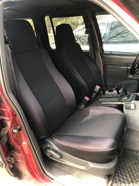 2000 Ford Explorer - Front bucket seats of a pickup or SUV fitted with black and gray neoprene seat covers, center console visible.