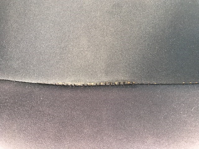 Close-up of frayed and damaged fabric seam on automotive upholstery