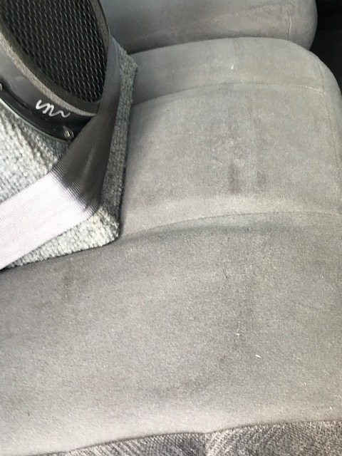 2000 Ford Explorer - Close-up of a gray cloth bench seat next to a door panel speaker and gray seat belt webbing.