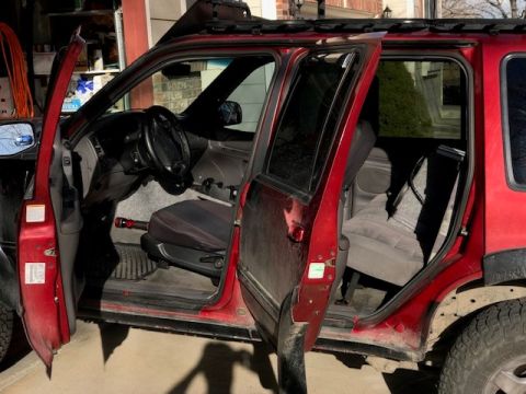2000 Ford Explorer - The interior of a red 2000 Ford Explorer is visible with all doors open, revealing the seats and dashboard.