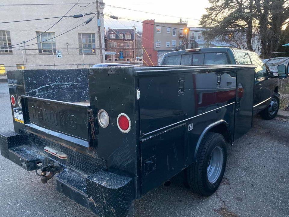 Black dually utility service truck with side toolboxes parked on a city street at dusk