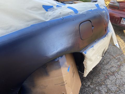2000 Pontiac Grand Prix - The rear quarter panel of a 2000 Pontiac Grand Prix is masked and prepped for painting, with another vehicle visible in the background.