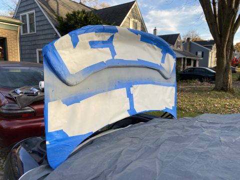 2000 Pontiac Grand Prix - A car hood, taped and primed, sits atop another vehicle outdoors.