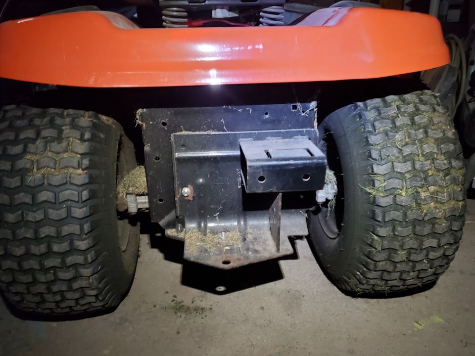 Orange lawn mower rear with two large tires and a metal hitch receiver