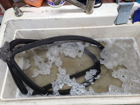 1995 Ford F-150 - A rubber seal and a piece of glass are being cleaned in a sink with soap and water.
