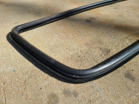 1995 Ford F-150 - A black rubber seal, likely for a car window, rests on a concrete surface.