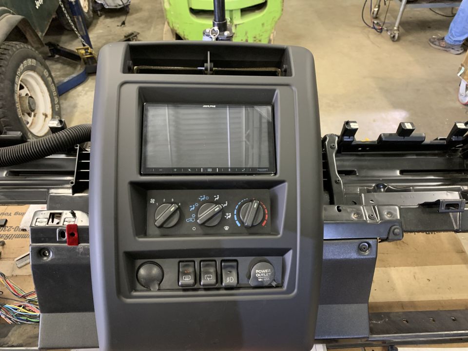Center console with Alpine stereo, climate controls, power outlet, and switches removed from a Jeep Cherokee