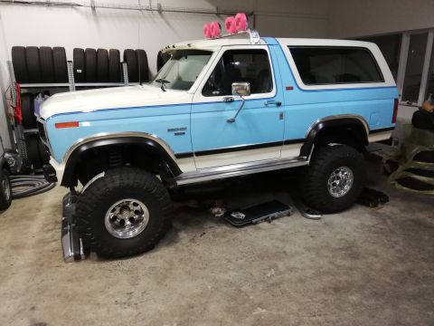 1996 Ford Bronco - This lifted Ford Bronco features a two-tone blue and white paint scheme and is shown in a garage setting.