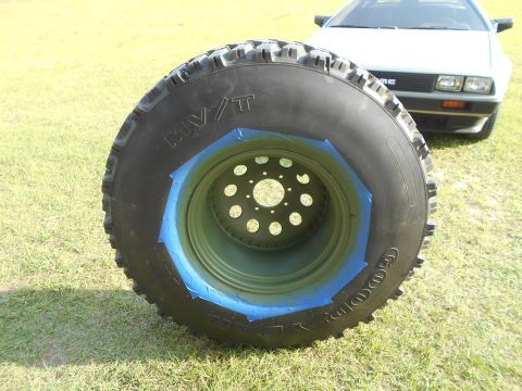 1992 Ford Bronco - A close-up of a tire and wheel assembly, with a DeLorean visible in the background.