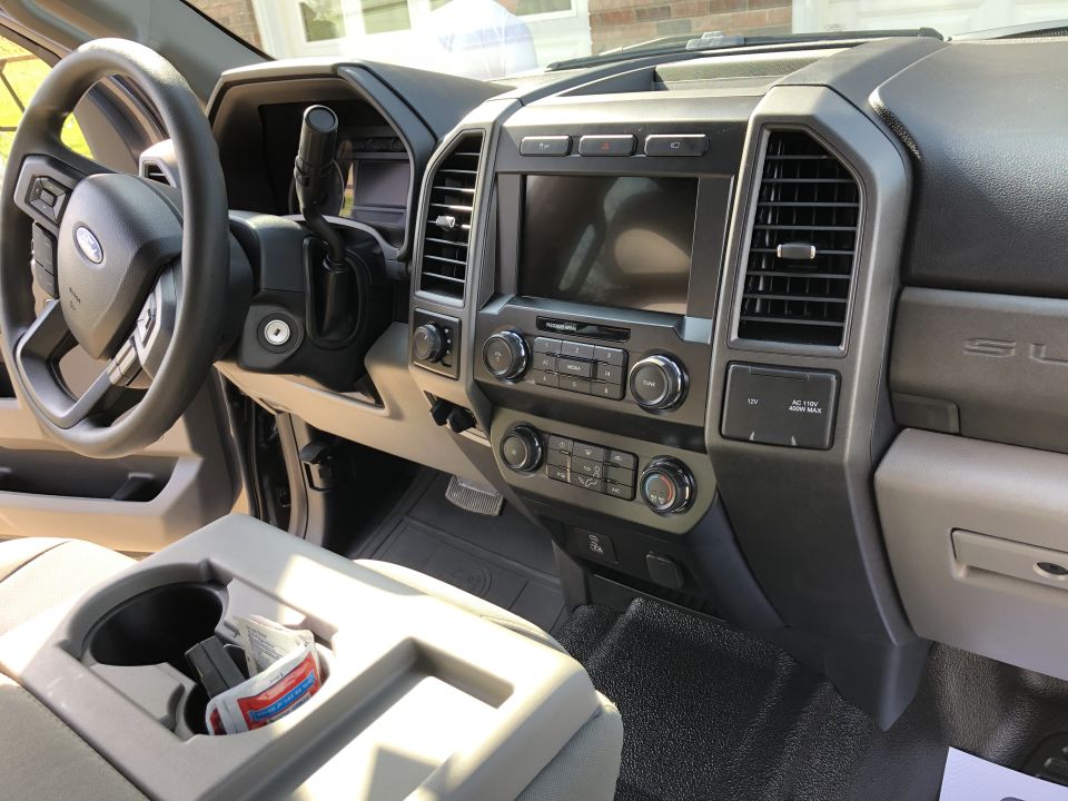 Gray dashboard and steering wheel of a Ford Super Duty truck, showing the center console and infotainment screen