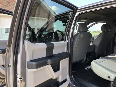 2021 Ford F-250 - The interior of a silver truck shows gray leather seats and a two-tone door panel with black and beige accents.