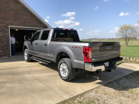 2021 Ford F-250 - This 2021 Ford F-250 Super Duty pickup truck is shown in a rear 3/4 view, parked in a driveway next to a brick garage.