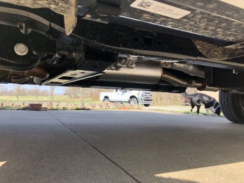 2021 Ford F-250 - A low-angle shot reveals the undercarriage of a vehicle, with another truck and a dog visible in the distance.