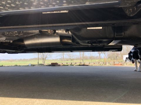 2021 Ford F-250 - The underside of a truck is visible, including the exhaust system and fuel tank, with a dog in the background.
