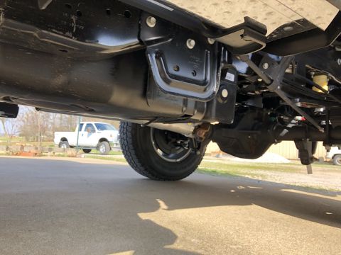 2021 Ford F-250 - Undercarriage of a white pickup truck, with another similar vehicle visible in the distance.