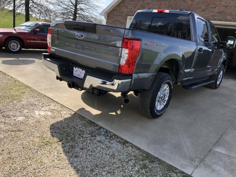 2021 Ford F-250 - A dark gray Ford Super Duty pickup truck is parked on a concrete driveway next to a maroon sedan.