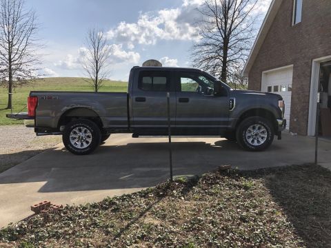 2021 Ford F-250 - A gray Ford F-250 Super Duty truck is parked on a concrete driveway in front of a brick house.