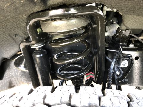 2021 Ford F-250 - Close-up of a truck's front suspension system, showing the coil spring and shock absorber.