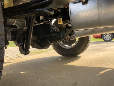 2021 Ford F-250 - The rear suspension and axle of a truck are visible, with a red car in the background.