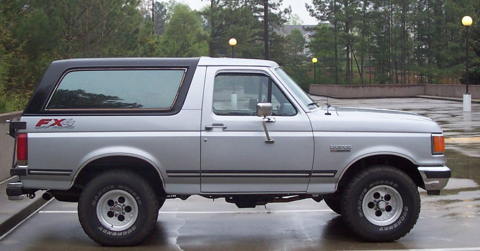 Silver Ford Bronco FX4 with black top, side view. Visible text: 'Bronco', 'FX4'