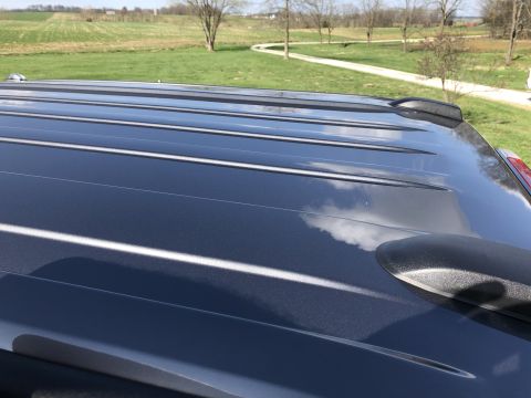 2021 Ford F-250 - The roof of a dark SUV is shown with roof rails and a shark fin antenna against a backdrop of fields and trees.