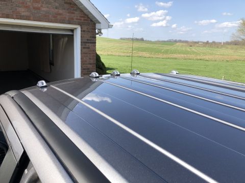2021 Ford F-250 - The roof of a gray truck is visible, equipped with clearance lights and an antenna, with a garage and grassy fields in the background.