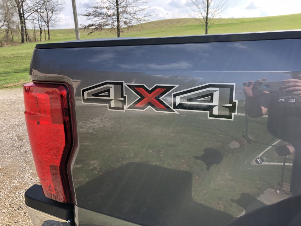 Gray Ford F-250 tailgate with 4x4 decal, red taillight, and SuperMotors.net logo