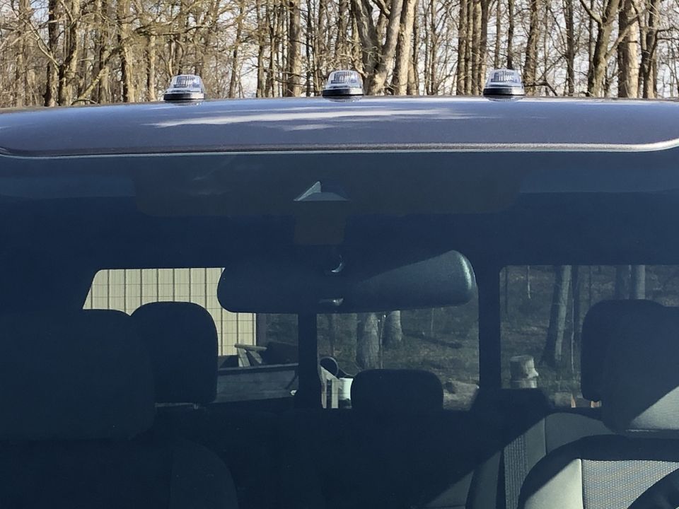 Rear view of a truck's roof with three amber lights and a rearview mirror inside