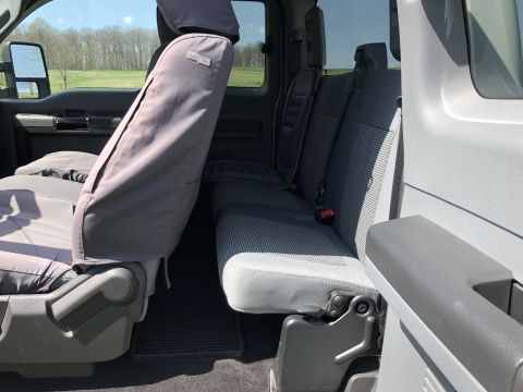 2011 Ford F-250 - The interior of a truck, gray fabric seats and seat covers, is visible from the side.