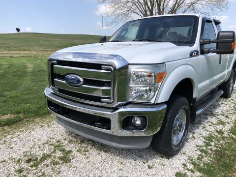 2011 Ford F-250 - A white 2011 Ford F-250 Super Duty truck is shown from a three-quarter front angle, parked outdoors on a gravel surface.