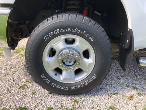 2011 Ford F-250 - Front wheel and fender detail of a white truck, BFGoodrich Trail T/A tires.