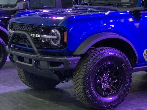 2021 Ford Bronco - The grille of a blue Ford Bronco shows the letters 'BRONCO' and a circular emblem.