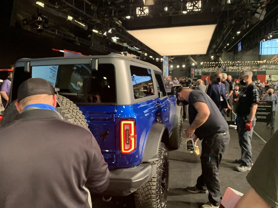 Blue 2021 Ford Bronco with spare tire on back, people around it at an event
