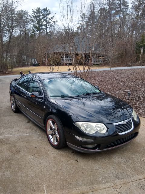 2002 Chrysler 300M - A black 2002 Chrysler 300M sedan is parked in a driveway on a cloudy day.