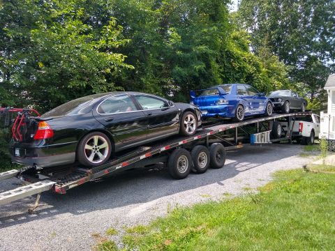 2006 Mitsubishi Evolution - A blue 2006 Mitsubishi Lancer Evolution VIII is loaded onto a car hauler with other vehicles.