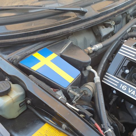 1991 Saab 900 - Close-up of a vehicle's engine bay, a Swedish flag sticker on a component.