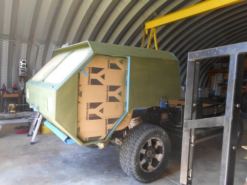 1992 Ford Bronco - A custom green camper shell is being built on a truck chassis, with cardboard boxes stacked inside.