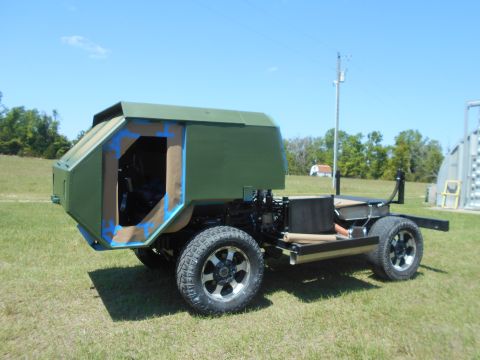 1992 Ford Bronco - This custom vehicle chassis is partially assembled with green body panels and an open doorway, set against a clear blue sky.