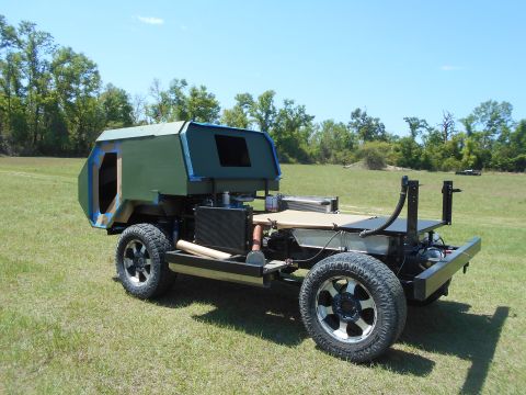 1992 Ford Bronco - This custom vehicle chassis with a green boxy cabin is seen outdoors on a sunny day.