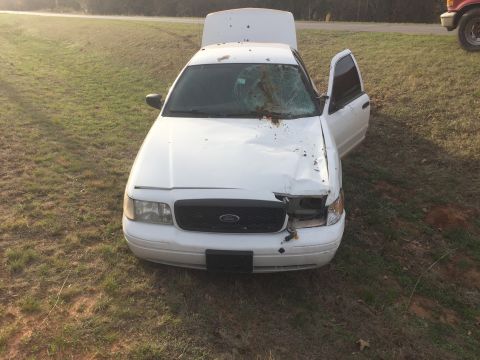 2005 Ford Crown Victoria - White 2005 Ford Crown Victoria shows significant front-end damage and has its hood and driver's door open.