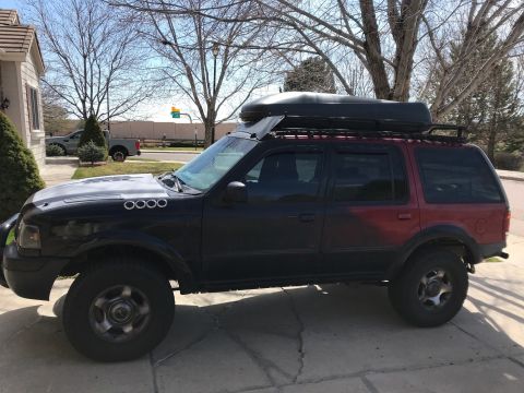 2000 Ford Explorer - Side view of a modified 2000 Ford Explorer SUV equipped with a roof rack and cargo carrier.