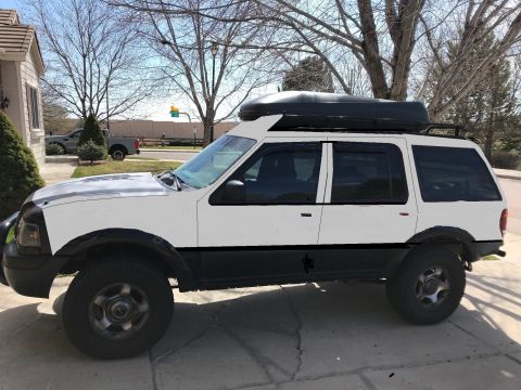 2000 Ford Explorer - This SUV is parked in a driveway with a house and trees in the background.
