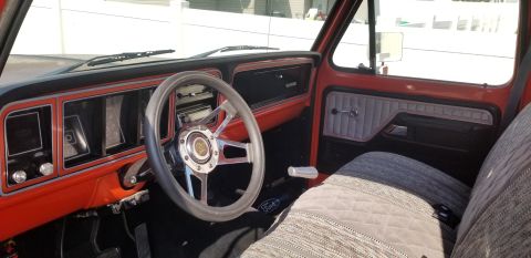 1977 Ford F-150 - The interior of a truck features a custom steering wheel and upholstered seats.