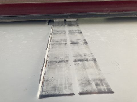 2015 Ford F-550 - Close-up view of a vehicle's undercarriage, showing wear and tear on a specific part, with a red trim piece visible overhead.