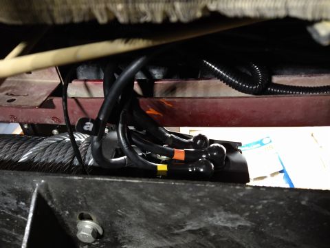 1996 Ford Bronco - Close-up view of winch cable and wiring harness components mounted on a vehicle frame.