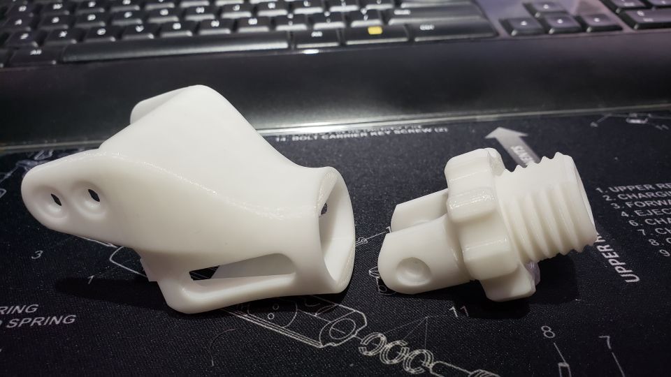 Two white 3D printed parts on a black surface with diagrams and text